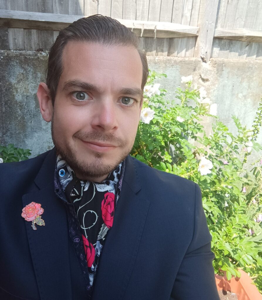 Karl Mercer is a young white man. He wears a smart suit and colourful silk cravat