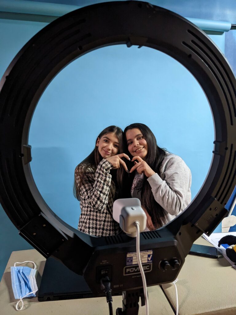 Two young people sit and make a hand heart with their two hands